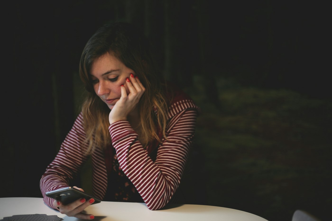 A young woman, chin in hand, reading her phone in a quiet moment